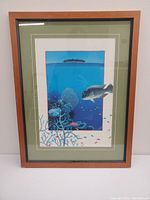 Photo showing one framed underwater scene with fish, coral, and distant island inside wooden frame with glass and green matting