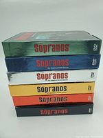 Stack of Sopranos DVD box sets, complete seasons from 1 to 6 in various colored cases.