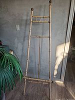 Bamboo easel standing upright against a wall on wood flooring, solid bamboo construction with natural finish and visible signs of use.