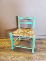 Front view of the vintage green chalked wooden children's chair with rush woven seat