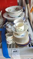 Overview of the bowls, plates, and teacups stacked together showing floral designs and gold trim