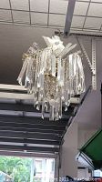 Full view of the chandelier hanging from the ceiling, showing the acrylic prisms and metal frame.
