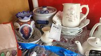 Overview showing multiple porcelain items including teapot, vases, plates, and bowl in shelf