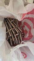 Plastic bag filled with multiple tubular metal cabinet handles in stainless steel finish.