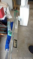 Side view of folded Gorilla aluminum ladder surrounded by other household items.