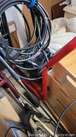 Close-up photo showing multiple black hoses coiled and attached to a red frame component of the pressure washer unit.