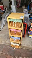 Frontal view of the wood shelf with four wicker baskets each with a different colored fabric liner.
