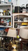 Wooden shelving unit behind and beside the plastic unit, displaying shelves and items, visible surfaces dusty and in used condition.