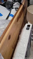 Side view of the wooden tabletop, showing wood grain and natural finish with minor wear.
