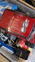 Photo showing top view of red remote control truck with number 1 decal and assorted remote control units in a plastic bin
