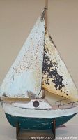 Front view of wooden sailboat sculpture showing detailed hull and rusted metal sails.