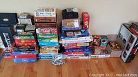 Wide view showing the full assortment of board games, puzzles, and Lego pieces stacked on the floor.