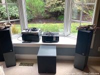 Overall view of four floor speakers, subwoofer and two stacks of stereo components on window ledge