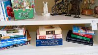 Books on the bottom shelf including health, historical and religious titles along with a green box labeled 'Toys' and white porcelain rabbit figurine on the upper shelf.