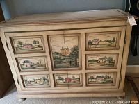 Front view of hand painted cabinet showing scenic countryside paintings on panels.