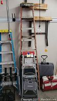 Full view of all items showing three ladders, stepstools, luggage racks, and saw horses
