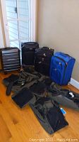 Nine pieces of luggage grouped—four wheeled suitcases and five duffle bags in black and green tones