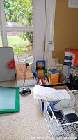 Overview of various office supplies and organizer items on a light carpet by window.
