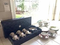 Overview of demitasse set in presentation box alongside additional cups and plates on tiled surface