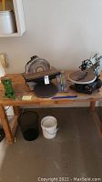 Overall view of wooden workbench with green vise, disc sander, scroll saw, and tool holder