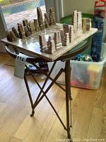 Chess set on a round table, showing stone abstract chess pieces arranged on the marble board