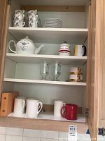 Photos showing cabinet shelving with various teapots, cups, mugs, saucers, and glassware arranged inside.