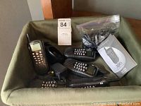Five black TriSquare XS walkie talkies with numeric keypads, antennas, a charging dock with power adapter, user manual and other accessories packed in a plastic bag.