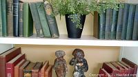 Shelving with vintage books, faux plant, and two ceramic figurines