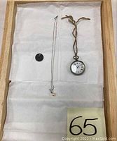 Overview photo showing all three items: sterling pocket watch, six pence coin pendant, and 14K white gold necklace with sapphire and pearl pendant on white fabric