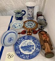 All items in the lot including ceramics, plates, mugs, carved wood birds and statue with a clear view to size and color.