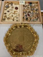Full lot view showing two wooden trays filled with assorted costume jewelry items and an ornate gold wash serving tray below.