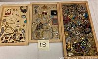 Three wooden trays filled with assorted jewelry items