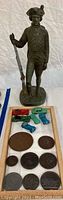 Overview of tin soldier statue, toy cars and medallions on tray