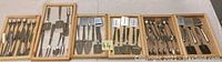 Full overview of flatware pieces displayed in wooden trays