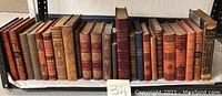 Full side view showing all books in the lot lined up side by side with visible ornate spines and some wear from use.