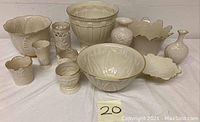 Front view showing all 11 Lenox white ceramic pieces including large and small vases, bowl, and serving dish with gold trim and embossed patterns.