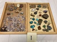 Two wooden trays containing varied mineral rocks and polished stones, including amethyst clusters, quartz pieces, and other assorted minerals.