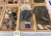 Overview of mineral and rock specimens on wooden trays including the amethyst cluster