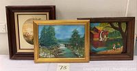 Three framed oil paintings: floral still life, river landscape, and colorful waterside scenery.