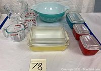 Overview: mixing bowl, two measuring cups, measuring bowl, yellow casserole dish, three colored storage dishes