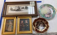 Lot overview showing watercolor painting, three framed portrait prints, and two porcelain plates