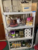 Front view of one plastic shelving unit with various household items on the shelves showing size and design.