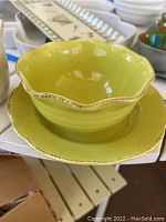 Olive green scalloped edge bowl stacked with matching plate, showing distressed rims and glossy interior finish.