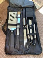 Photo of one barbecue tool set in black carrying case showing spatula, fork, tongs, and brush secured inside