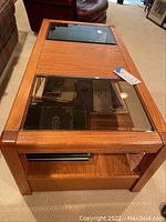 Top-down view showing the rectangular wood frame with two beveled glass panels on top and the visible items stored underneath.