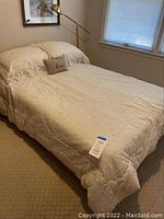 Full view of made bed with white bedding and decorative pillow in a bedroom.