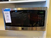 Front view of Kenmore microwave showing stainless steel frame, black mesh window, and digital control panel with display showing 11:05.