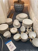Full set of fine Mikasa china including plates, cups, bowls, and serving pieces arranged on a carpeted floor.