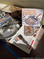 Photo displaying a professional steak pan packaging with an image of the pan and cooked steak, also showing a double burner rangetop griddle and some utensils