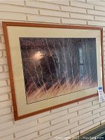 Framed birch tree print showing fall/winter scene with wood-tone frame and cream mat on white brick wall